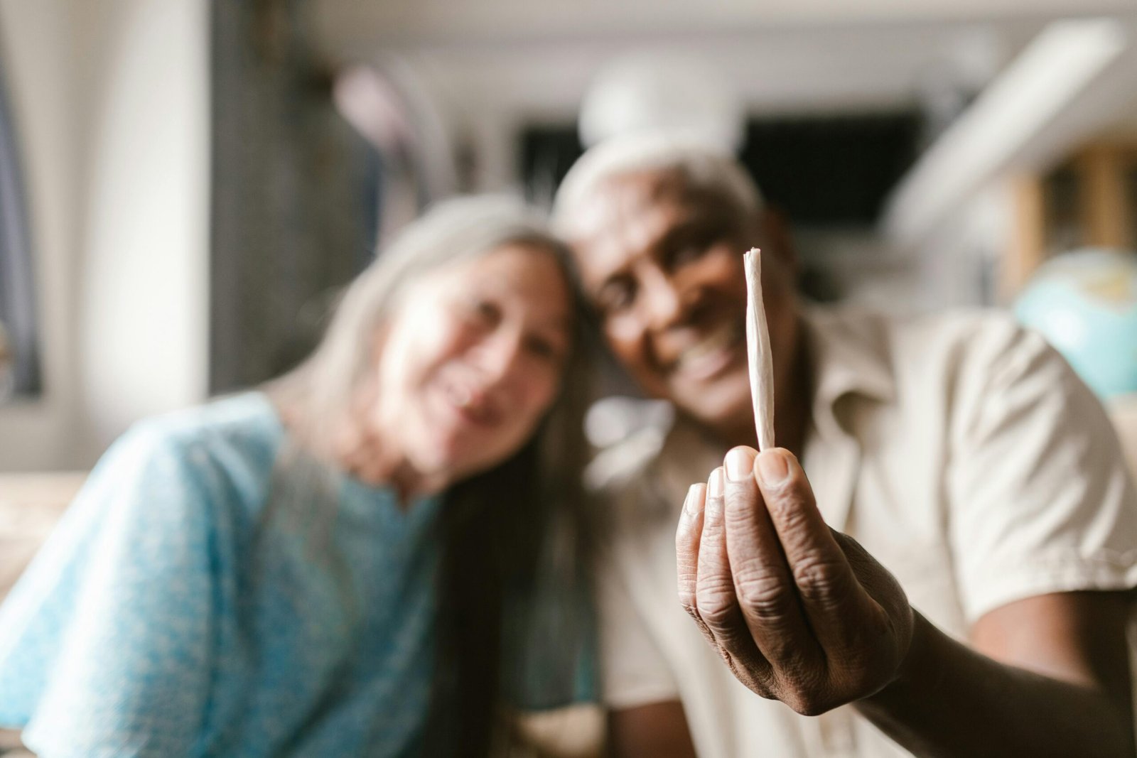 Joyful senior couple enjoying cannabis culture indoors.